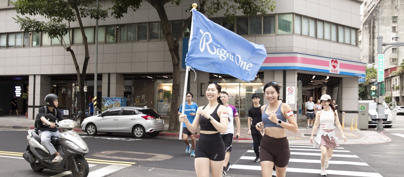 大稻埕街口,一群穿運動服的參加者跟著 Right One 藍色旗子笑著跑過斑馬線