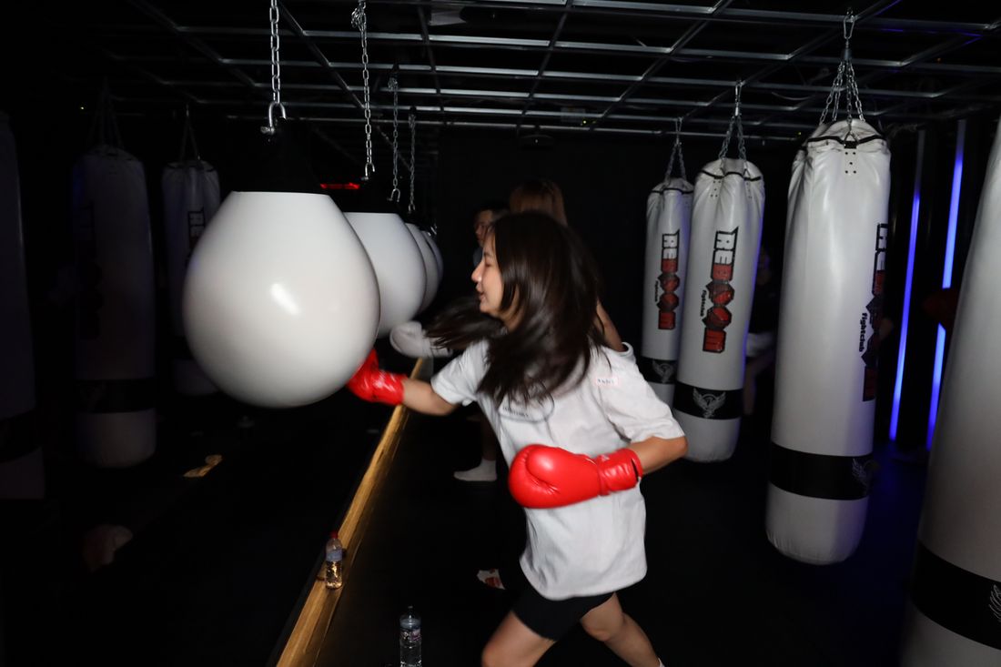 一位穿白色上衣的女生戴紅色手套向沙包出拳，動作帶著殘影