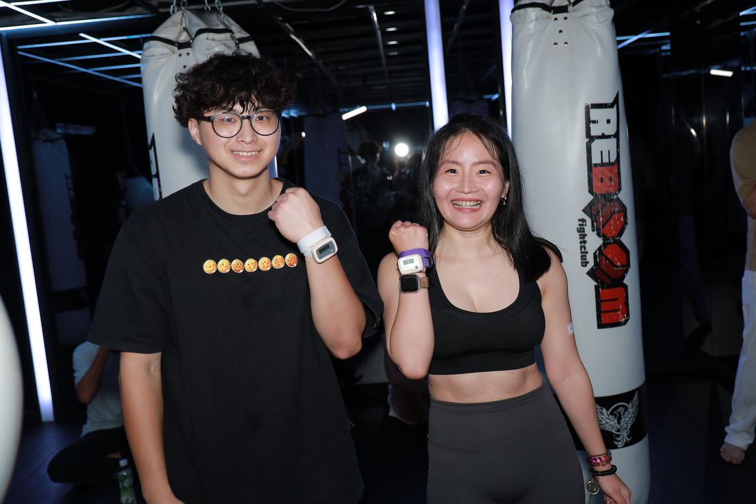 一男一女並肩比出加油手勢，手腕上戴著出拳計數器
