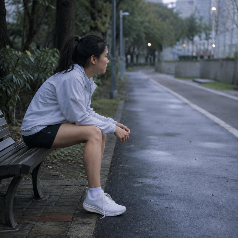 清晨的公園裡,一個人穿著跑鞋坐在長椅上,鞋帶還沒綁好