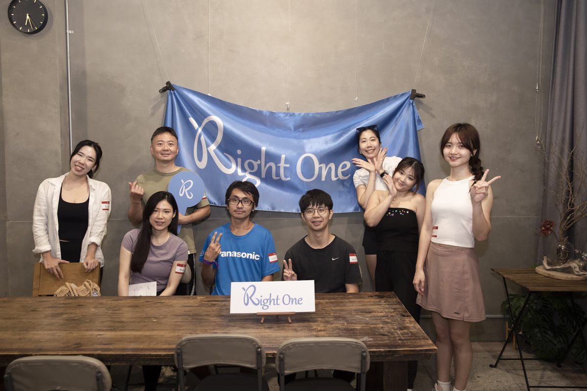 活動結束後的大合照,參加者在掛著 Right One 藍色布條的牆前站坐兩排,桌上立著 Right One 的牌子