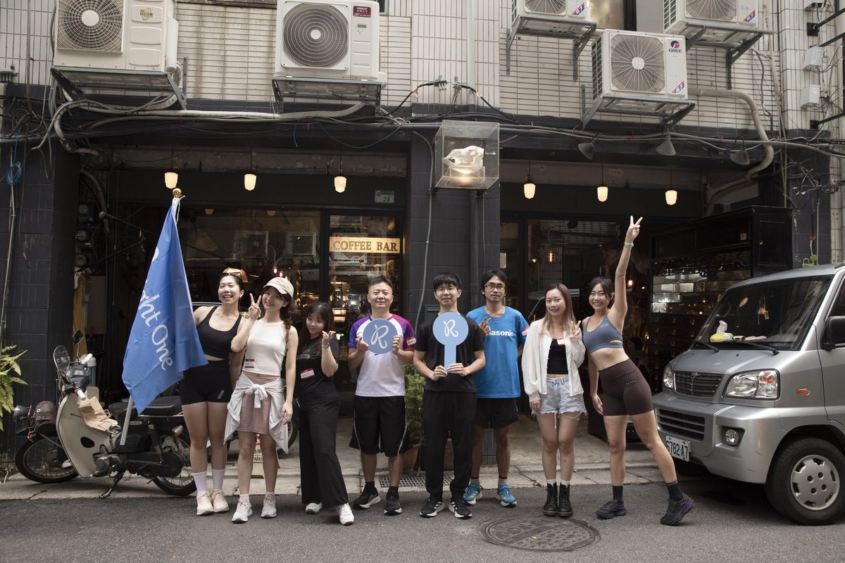 出發前,參加者在大稻埕街邊一間咖啡店門口排成一排合照,最左邊的人舉著 Right One 藍色旗子,幾個人手上拿著 R 字手拿板