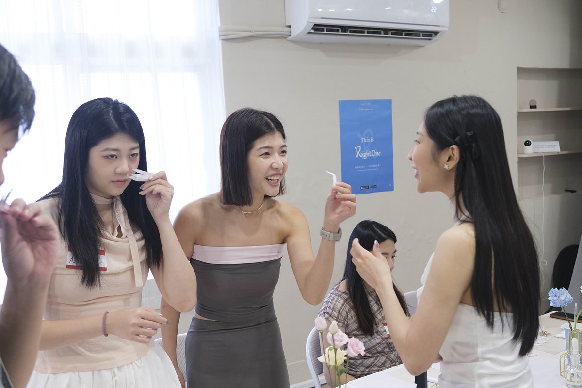 三位女生站在一起,各自舉著試香紙互相聞,其中一位笑得很開心